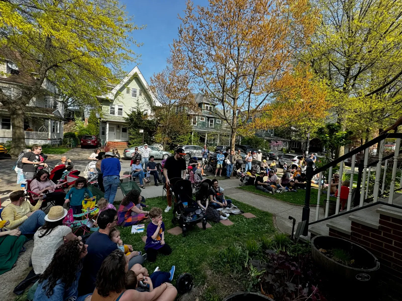 Neighbors gathered on a lawn watching a porch concert